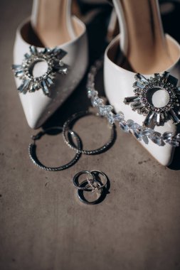 Gelin ayakkabısının arka planında değerli taşlar olan alyanslar.