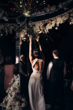 Yeni evliler şehrin üzerindeki gece havai fişeklerine bakıyorlar.