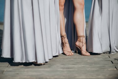 Bekarlığa veda partisinde zarif gece elbiseleri giyen nedimelerin bacakları.