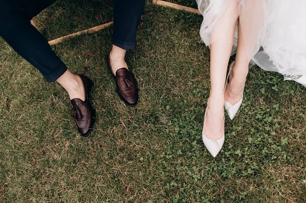 Yeni evliler çimlerin üzerinde durur, bacakları yakındır.