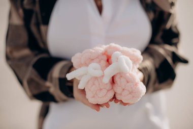 Elinde yeni doğmuş bir bebek için ayakkabı tutan hamile bir kız.