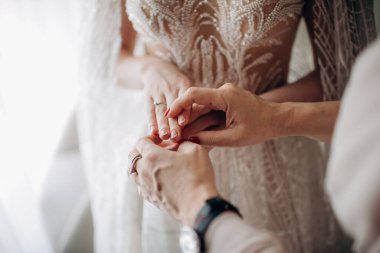 Anne gelinini ellerinden tutuyor.