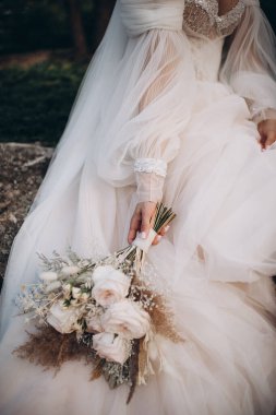 Gelin nazikçe düğün buketini tutuyor