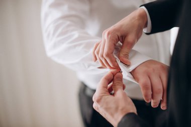 Damadın elleri ve kol düğmelerini takmaya yardım eden sağdıç.