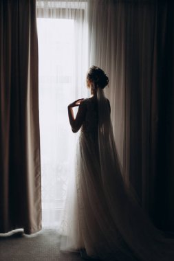 Gelinlik giymiş gelin pencerenin önünde.
