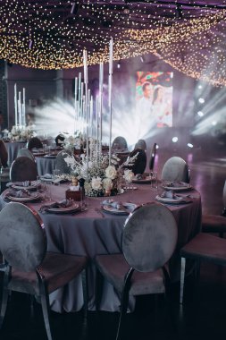 Yuvarlak servis masasında büyük bir çiçek aranjmanı var.