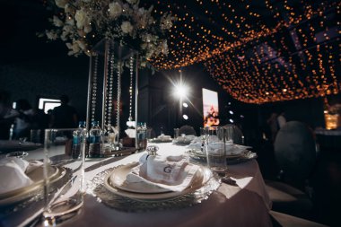 Yuvarlak servis masasında büyük bir çiçek aranjmanı var.