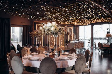 Yuvarlak servis masasında büyük bir çiçek aranjmanı var.