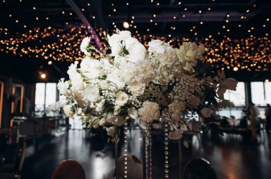 Düğün ziyafeti masasının dekorunda zarif bir çiçek aranjmanı.