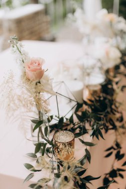 Düğün yemeği masasının dekorunda kırsal çiçek aranjmanı