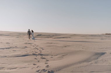 Kumsalda yürüyen çift.