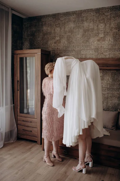 mother helping daughter put on wedding dress