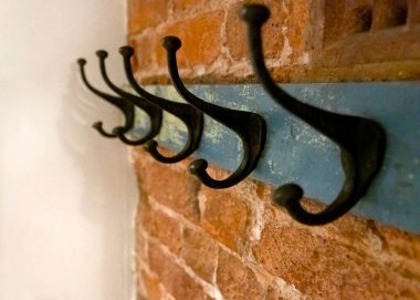 Wrought iron coat hangers place on old blue vintage wood hung on a brick textured wall with a blank leftside for copy space shot in selective focus with a narrow depth of field 