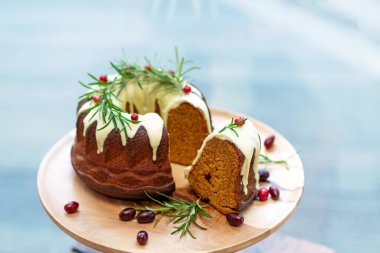 Noel karamelli pasta, kesilmiş, beyaz çikolata, kızılcık ve biberiye ile süslenmiş ahşap bir stantta. Şenlikli pişmiş yiyecekler. Yumuşak seçici odak.