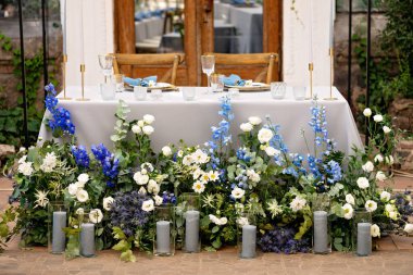 Yeni evliler için düğün masası kristal, altın çatal bıçak, taze çiçekler ve mumlarla dolu. Evlilik için dekor. Yumuşak seçici odak.