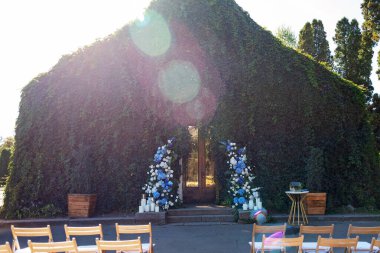 Tören için düğün kemeri. Taze beyaz güller, mavi orkideler ve mumlarla süslenmiş. Düğün dekoru. Yumuşak seçici odak.