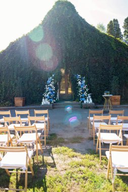 Tören için düğün kemeri. Taze beyaz güller, mavi orkideler ve mumlarla süslenmiş. Düğün dekoru. Yumuşak seçici odak.