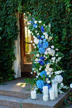 Taze beyaz güller, mavi orkideler ve mumlarla süslenmiş düğün dekorları. Düğün kemeri. Yumuşak seçici odak.