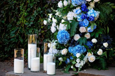 Taze beyaz güller, mavi orkideler ve mumlarla süslenmiş düğün dekorları. Düğün kemeri. Yumuşak seçici odak.