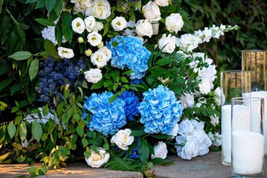 Taze beyaz güller, mavi orkideler ve mumlarla süslenmiş düğün dekorları. Düğün kemeri. Yumuşak seçici odak.