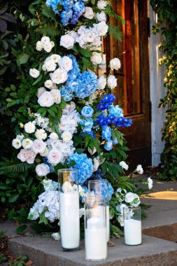 Taze beyaz güller, mavi orkideler ve mumlarla süslenmiş düğün dekorları. Düğün kemeri. Yumuşak seçici odak.
