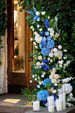 Taze beyaz güller, mavi orkideler ve mumlarla süslenmiş düğün dekorları. Düğün kemeri. Yumuşak seçici odak.