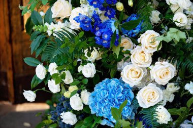 Taze beyaz güller, mavi orkideler ve mumlarla süslenmiş düğün dekorları. Düğün kemeri. Yumuşak seçici odak.