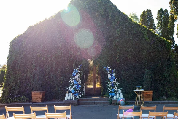 Tören için düğün kemeri. Taze beyaz güller, mavi orkideler ve mumlarla süslenmiş. Düğün dekoru. Yumuşak seçici odak.