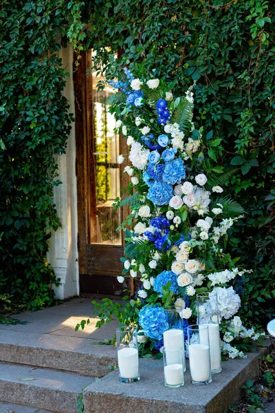 Taze beyaz güller, mavi orkideler ve mumlarla süslenmiş düğün dekorları. Düğün kemeri. Yumuşak seçici odak.