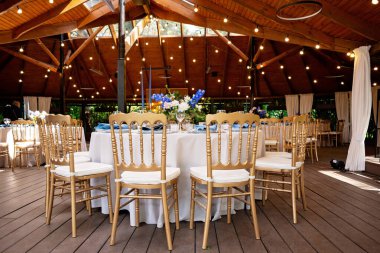 Şenlikli düğün, mavi keten peçeteler, mumlar, altın koltuklar ve taze çiçek buketleri. Düğün süslemeleri. Restoran menüsü konsepti. Yumuşak seçici odak.