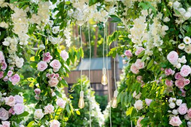 Düğünün kemeri. Beyazlı, ampullü taze çiçeklerden yapılmış. Yakın plan. Yumuşak seçici odak.