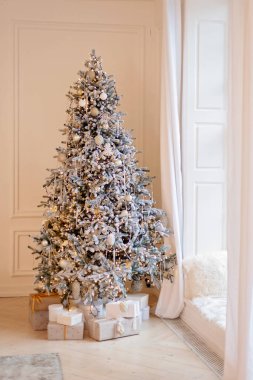 Yılbaşı ağacı dekoratif toplar ve bokeh ışıklarıyla süslenir, ışık odasının penceresinin yanındaki Noel hediye kutularıyla. Yumuşak seçici odak.