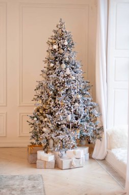 Yılbaşı ağacı dekoratif toplar ve bokeh ışıklarıyla süslenir, ışık odasının penceresinin yanındaki Noel hediye kutularıyla. Yumuşak seçici odak.