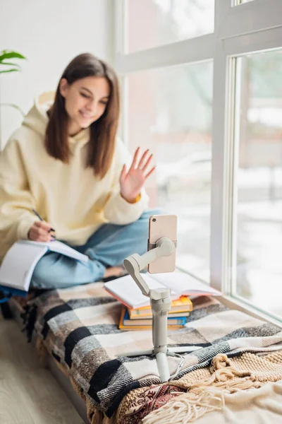 Teen school girl distant school or college student virtual remote e learning using mobile phone app in bedroom. Distance education classes, studying online at home concept. Soft selective focus.