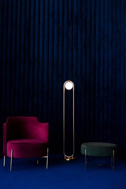 Konforlu kırmızı kadife koltuğu, minimalist lambası, yeşil pouf 'u ya da koyu mavi kadife duvar panelleri ve zemin döşemesi olan bir daire..