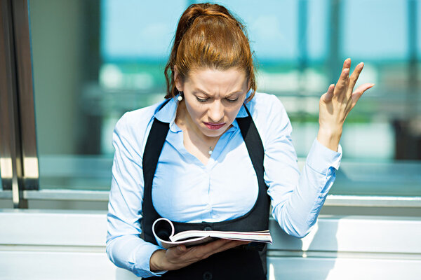 Business woman reading magazine, confused