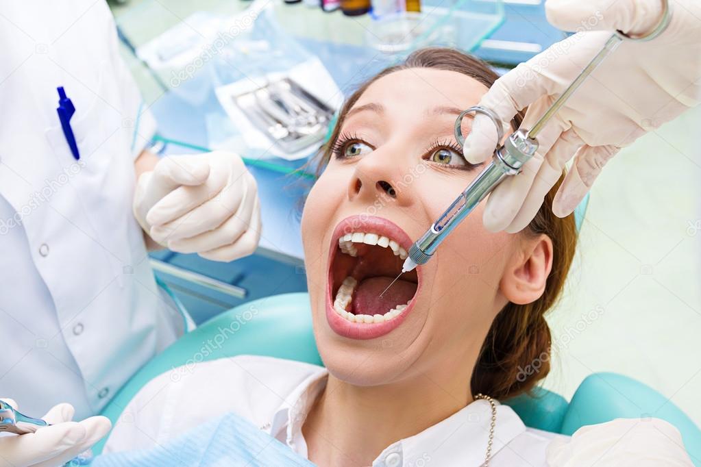 Female patient in dentist office getting anesthesia before tooth