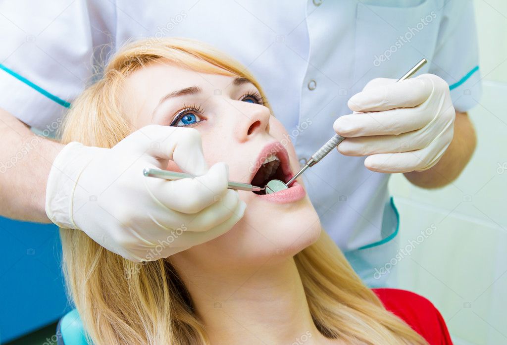 Dentist examining young adult patient, doing cleaning of teeth