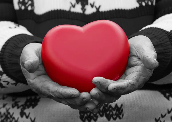 Manos mayores, anciana sosteniendo el corazón rojo — Foto de Stock