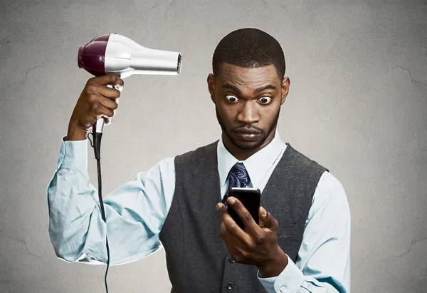 Businessman texting while using haidryer — Stock Photo, Image