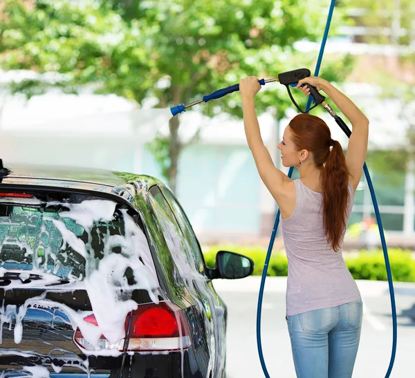 Молодая женщина моет машину — стоковое фото