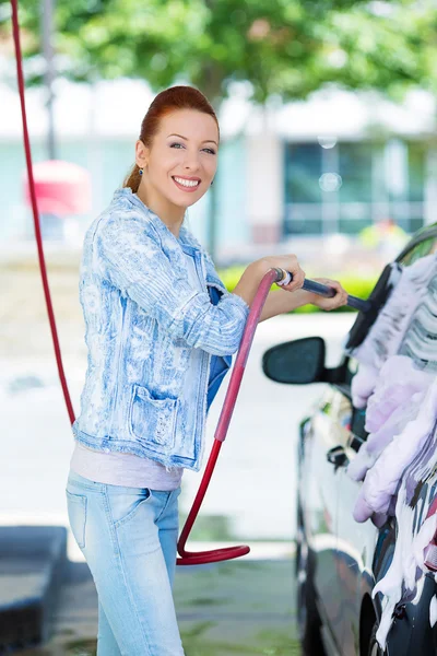 Sorridente giovane donna lavaggio, pulizia della sua auto compatta — Foto Stock