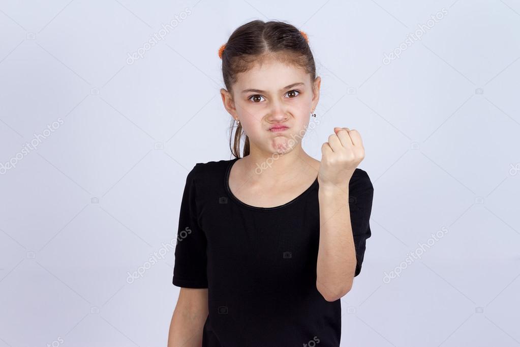 Angry little girl showing fist to someone