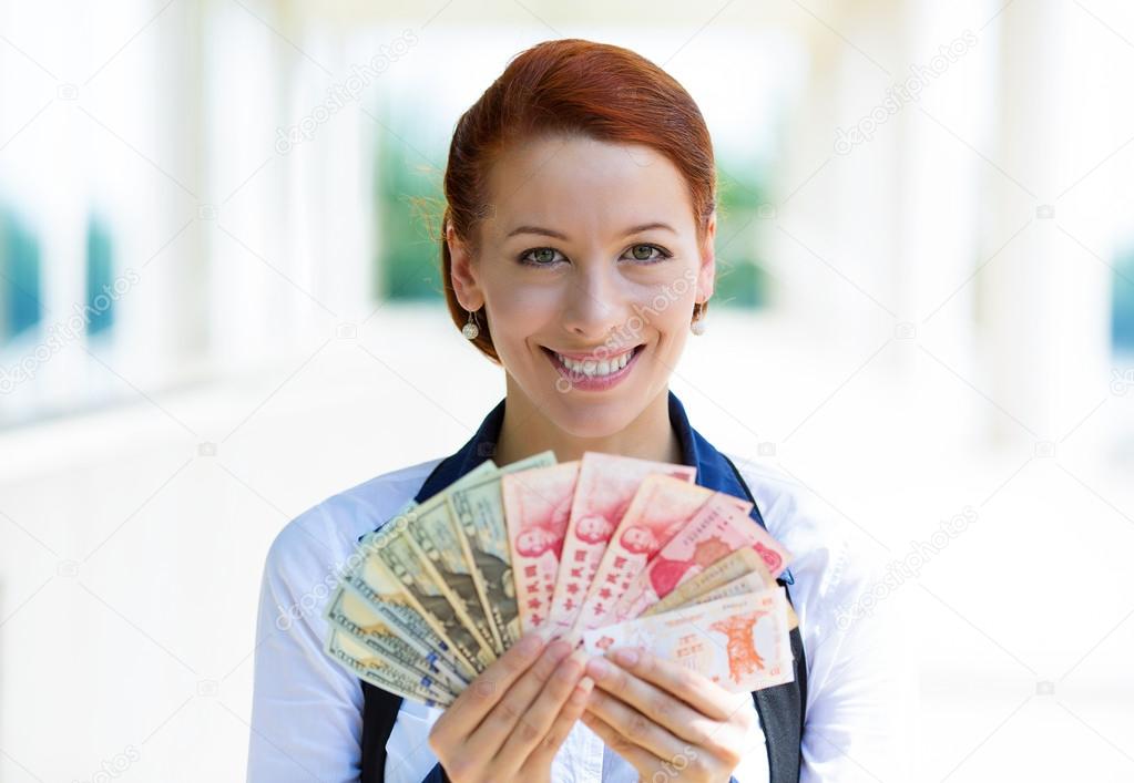 Excited business woman holding currency of different countries