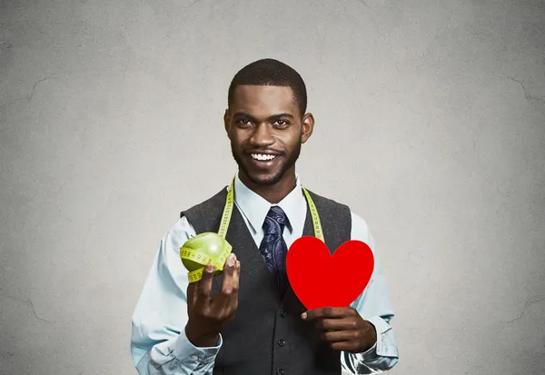 Человек держит зеленое яблоко и сердце — стоковое фото