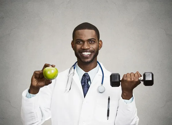 Happy doctor holding green apple, dumbbell — Stock Photo, Image