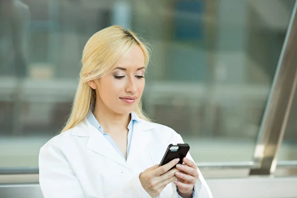 Feliz mujer médico mensajes de texto en el teléfono inteligente — Foto de Stock