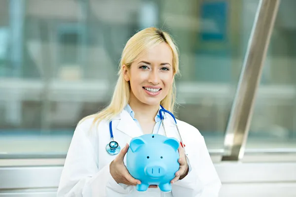 Happy health care professional, doctor, nurse holding piggy bank — Stock Photo, Image