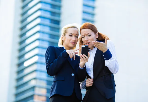 Portrait of two unhappy, dissatisfied business women reading som — Stock Photo, Image