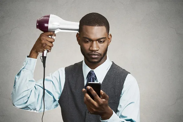 Výkonný drží chytrý telefon, vysycháním vlasy — Stock fotografie
